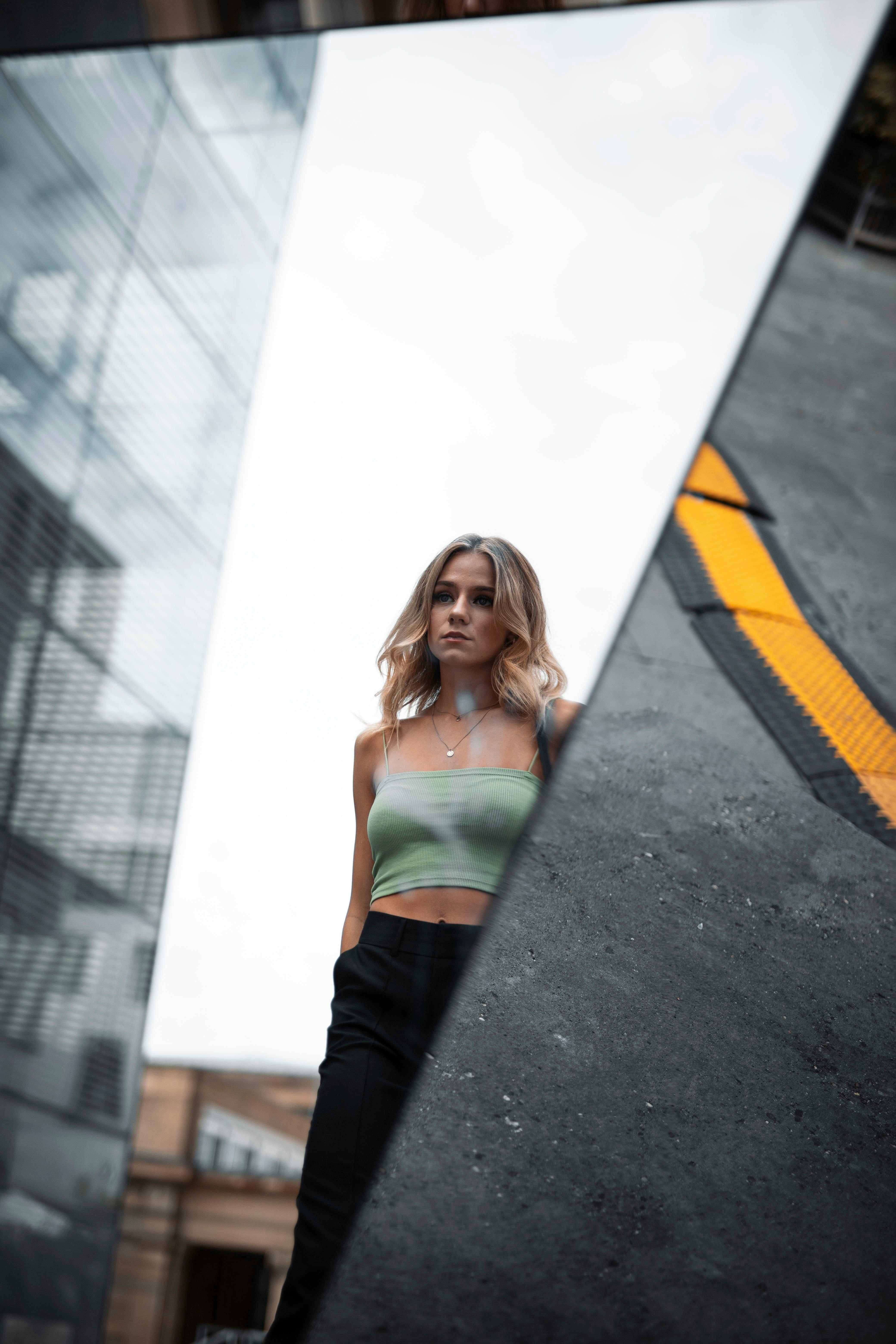 woman in white tank top and black pants standing on road during daytime